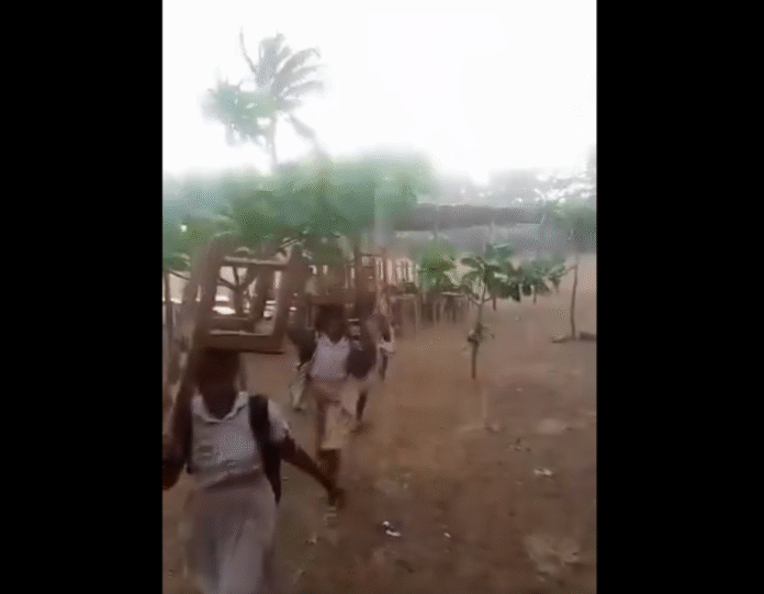 The Ketu South student carrying their desk in the heavy downpour