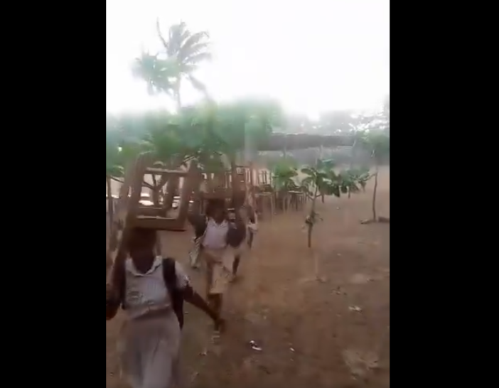 The Ketu South student carrying their desk in the heavy downpour